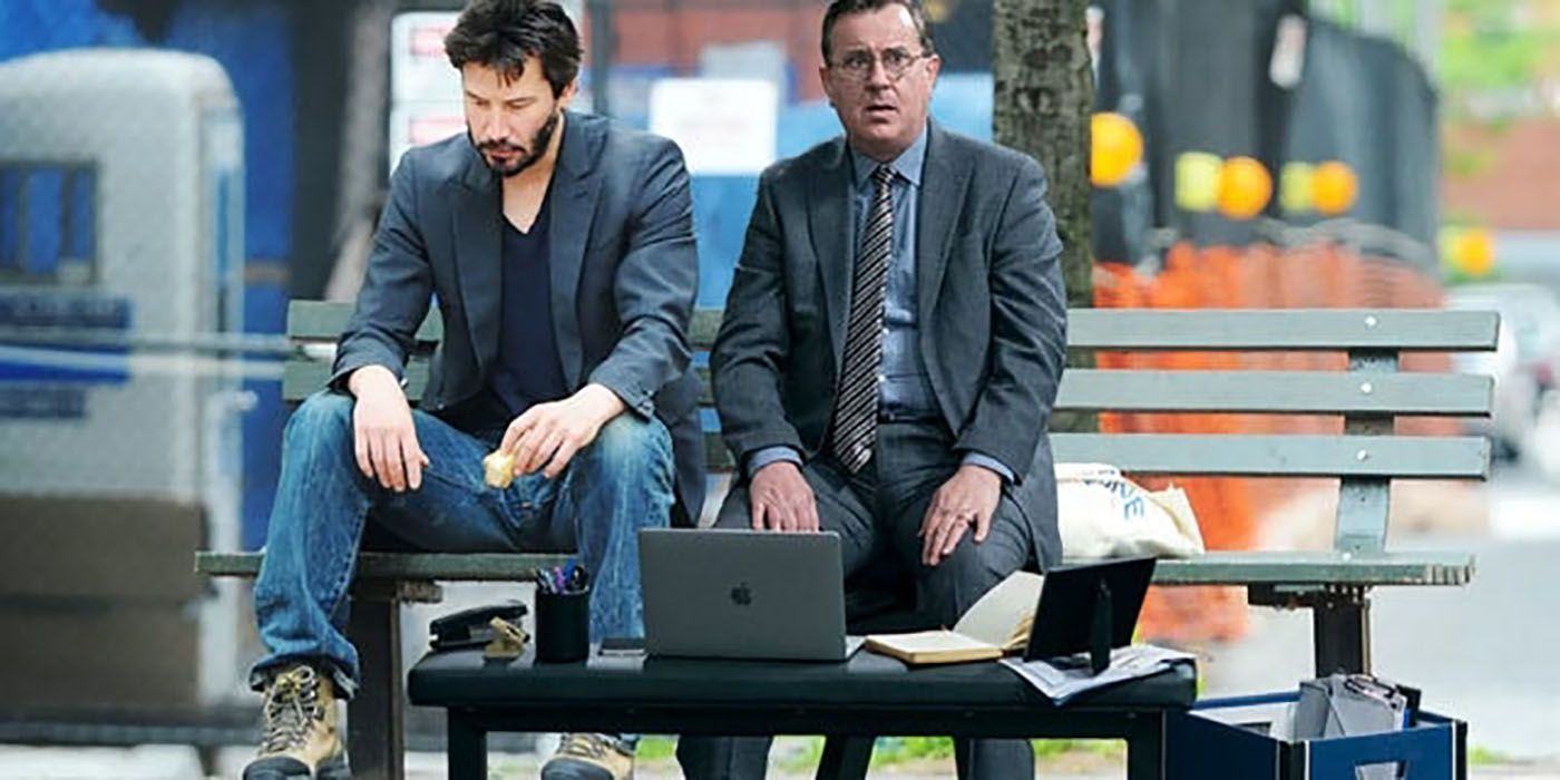 Ted Lasso's Higgins and his Photostopp laptop sit next to Keanu Reeves on a park bench.