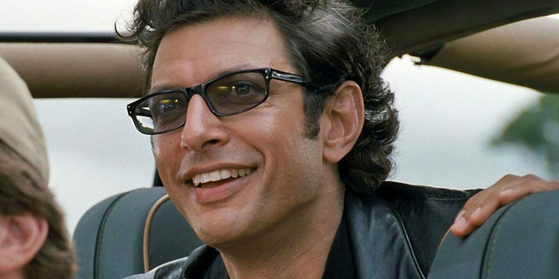 Jeff Goldblum smiles with black shades on in Jurassic Park.